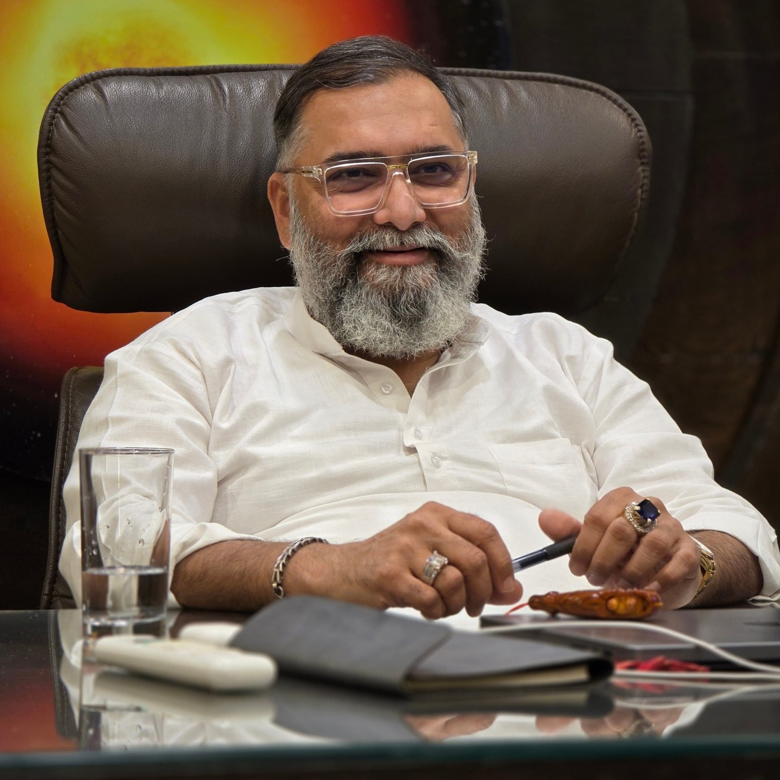A man with glasses and a beard is seated at a desk, engaged in a task.